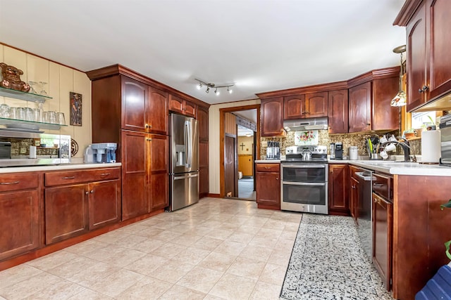 212 W Main St, Hillsborough, NH 03244 - kitchen featuring appliances with stainless steel finishes, under cabinet range hood, a sink, backsplash, and reddish brown cabinets