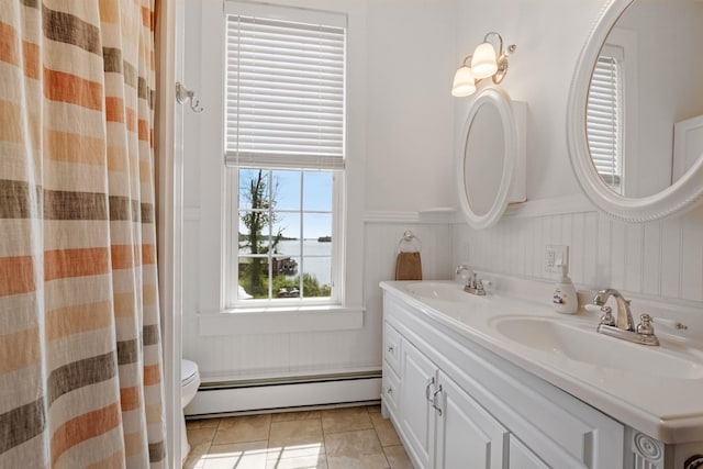 10 Wharf Rd, Center Harbor, NH 03226 - full bath featuring baseboard heating, double vanity, toilet, a wainscoted wall, and tile patterned flooring