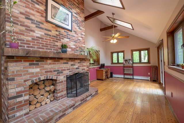 16 Berkeley St, Pelham, NH 03076 - living area featuring a skylight, a baseboard heating unit, high vaulted ceiling, a fireplace, and light wood-style floors