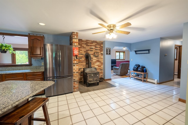 16 Berkeley St, Pelham, NH 03076 - kitchen featuring freestanding refrigerator, a wood stove, a ceiling fan, light tile patterned flooring, and brown cabinetry