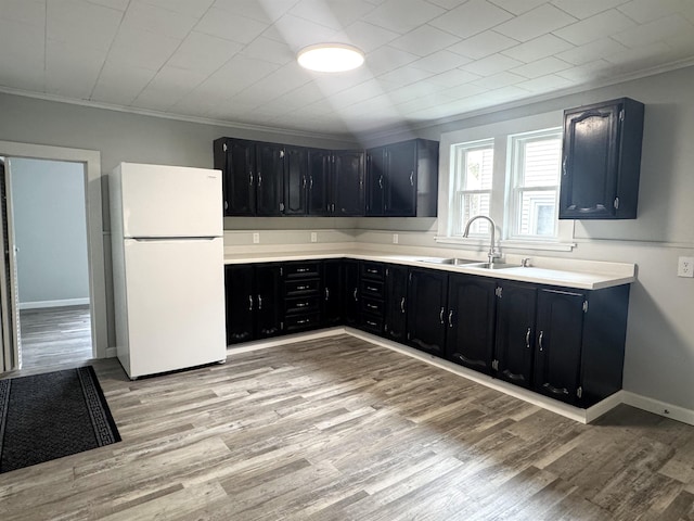217 Clyde St, Newport City, VT 05855 - kitchen with freestanding refrigerator, dark cabinets, crown molding, a sink, and light wood-style flooring