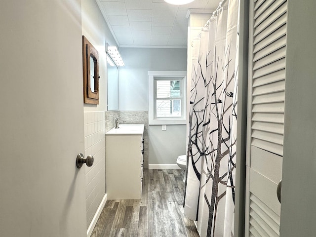217 Clyde St, Newport City, VT 05855 - bathroom featuring tile walls, toilet, vanity, wood finished floors, and wainscoting