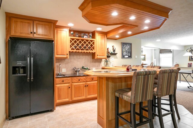 16 Gilboa Ln, Nashua, NH 03062 - kitchen featuring black fridge with ice dispenser, a kitchen breakfast bar, light tile patterned flooring, recessed lighting, and a center island