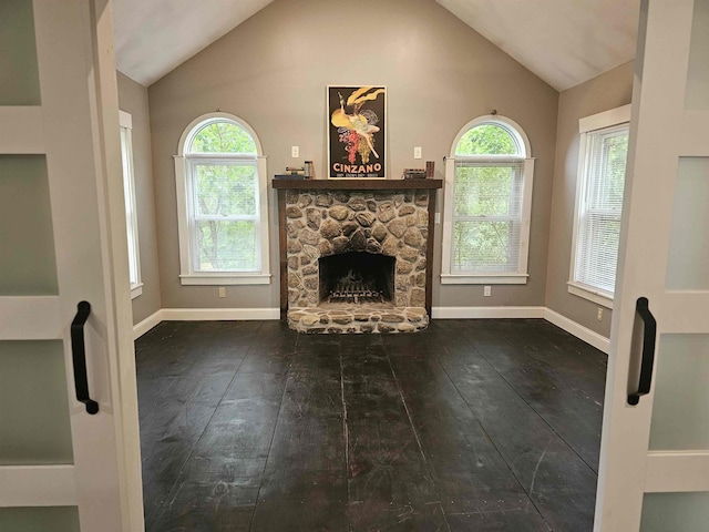 436 Mammoth Rd, Pelham, NH 03076 - unfurnished living room with wood-type flooring, vaulted ceiling, a stone fireplace, plenty of natural light, and baseboards