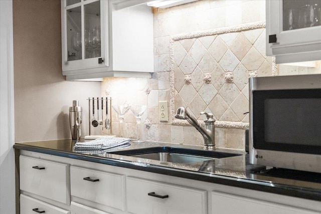 1097 Taber Ridge Rd, Stowe, VT 05672 - kitchen with stainless steel microwave, decorative backsplash, dark countertops, a sink, and white cabinets