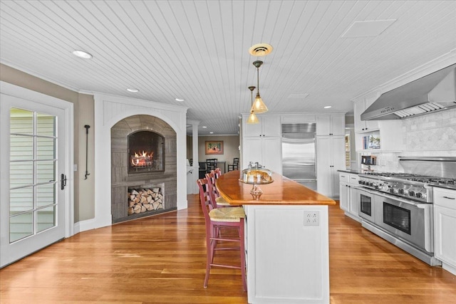 1097 Taber Ridge Rd, Stowe, VT 05672 - kitchen with high end appliances, light wood finished floors, a kitchen bar, white cabinetry, and recessed lighting