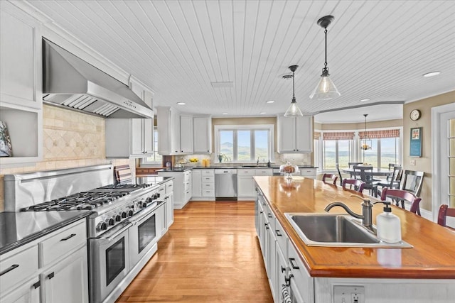 1097 Taber Ridge Rd, Stowe, VT 05672 - kitchen with stainless steel appliances, wall chimney range hood, a sink, wood counters, and recessed lighting