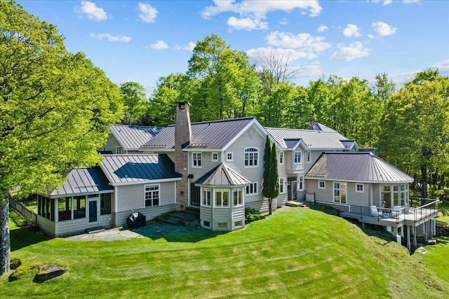 1097 Taber Ridge Rd, Stowe, VT 05672 - rear view of house featuring a standing seam roof, a chimney, a sunroom, metal roof, and a yard