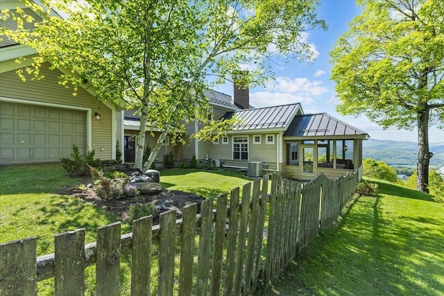 1097 Taber Ridge Rd, Stowe, VT 05672 - rear view of house with a standing seam roof, a garage, central air condition unit, metal roof, and a chimney