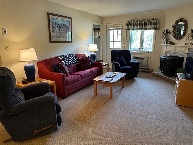 227 Main St Unit 232, Lincoln, NH 03251 - carpeted living room with a wood stove and a wall unit AC