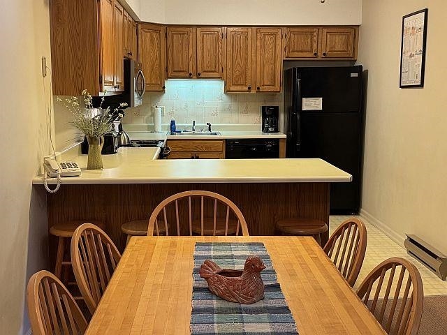 227 Main St Unit 232, Lincoln, NH 03251 - kitchen featuring black appliances, light countertops, a sink, a peninsula, and a baseboard heating unit