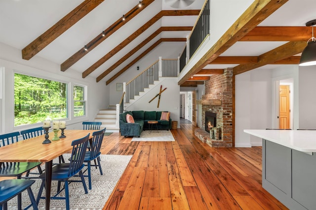 47 Hollow View Rd, Stowe, VT 05672 - dining area with stairway, beamed ceiling, wood-type flooring, a brick fireplace, and high vaulted ceiling