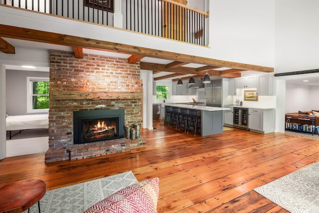 47 Hollow View Rd, Stowe, VT 05672 - living room featuring light wood-style floors, a towering ceiling, beverage cooler, a brick fireplace, and beamed ceiling