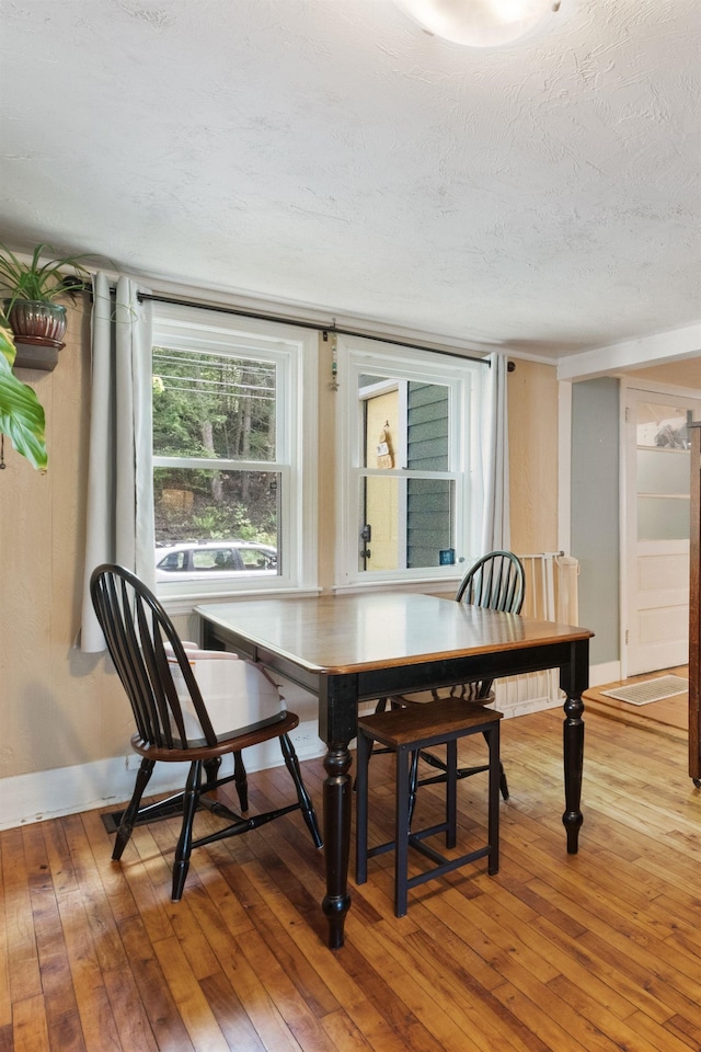 194 Pleasant St, Bristol, NH 03222 - dining room featuring light wood-type flooring, a textured ceiling, and baseboards