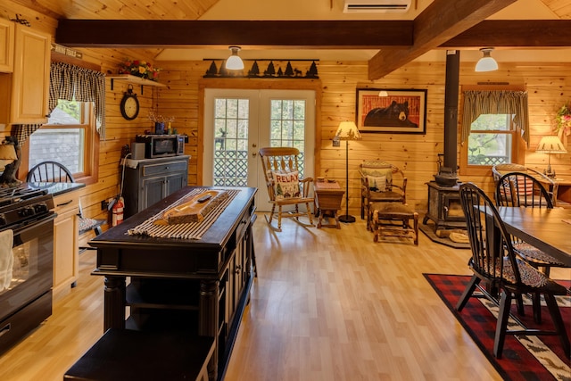 3233 Stinson Lake Rd, Ellsworth, NH 03266 - kitchen featuring beam ceiling, black gas range oven, wooden walls, light wood-type flooring, and a wood stove