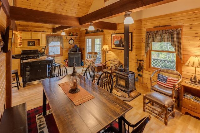 3233 Stinson Lake Rd, Ellsworth, NH 03266 - dining space featuring a wood stove, wood walls, and light wood-style flooring