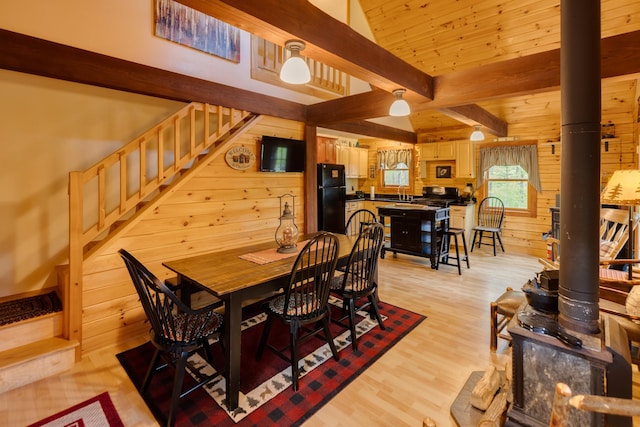 3233 Stinson Lake Rd, Ellsworth, NH 03266 - dining space featuring a wood stove, wood walls, stairway, beam ceiling, and light wood finished floors