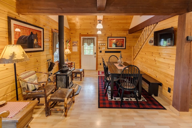 3233 Stinson Lake Rd, Ellsworth, NH 03266 - dining space featuring beamed ceiling, wood walls, wood finished floors, and a wood stove