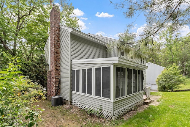 5 Christian Dr, Nashua, NH 03063 - view of side of home featuring a sunroom, a chimney, central AC, and a lawn