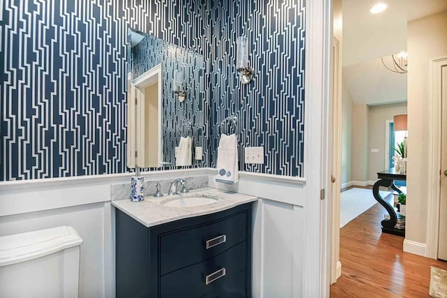 12 Haywick Dr, Stratham, NH 03870 - bathroom featuring vanity, wood finished floors, toilet, baseboards, and a chandelier