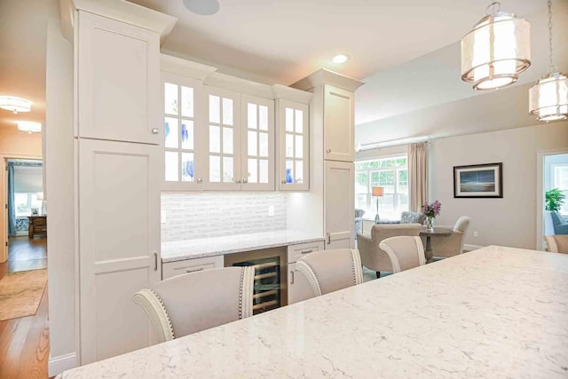 12 Haywick Dr, Stratham, NH 03870 - kitchen featuring wine cooler, light stone countertops, white cabinetry, glass insert cabinets, and wood finished floors