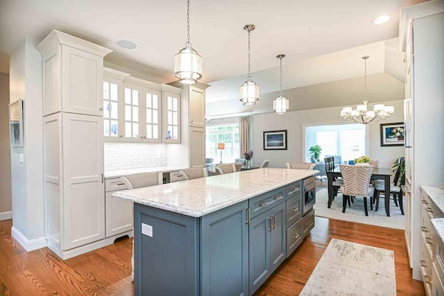 12 Haywick Dr, Stratham, NH 03870 - kitchen with white cabinets, wood finished floors, a center island, decorative light fixtures, and light stone countertops