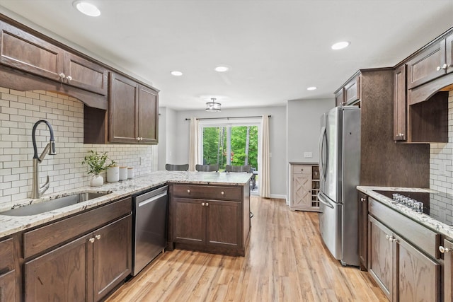 16 Ches Mae Ln, Milford, NH 03055 - kitchen with stainless steel appliances, a sink, a peninsula, backsplash, and light wood-type flooring