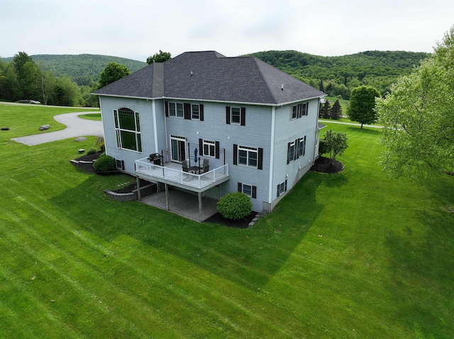 275 Petit Rd, Coventry, VT 05825 - back of property with a shingled roof, a yard, a wooden deck, and a forest view