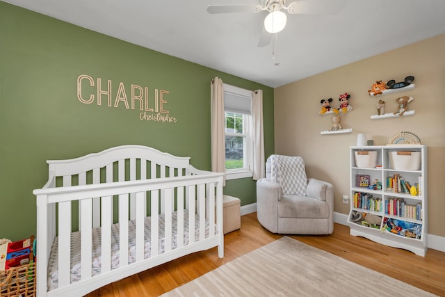 190 Anthony St, Manchester, NH 03103 - bedroom featuring wood finished floors, a crib, baseboards, and a ceiling fan