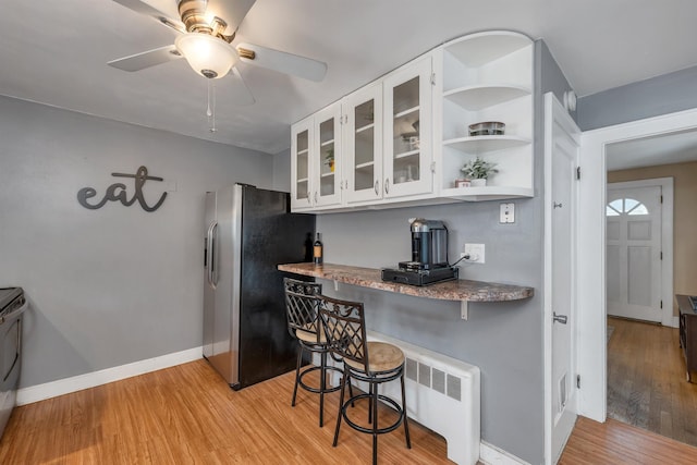190 Anthony St, Manchester, NH 03103 - kitchen with stainless steel fridge, light wood-type flooring, glass insert cabinets, a breakfast bar area, and baseboards