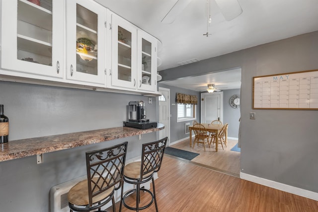 190 Anthony St, Manchester, NH 03103 - kitchen with a ceiling fan, light wood-style flooring, baseboards, white cabinets, and glass insert cabinets