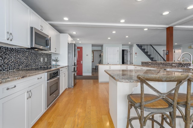 26 Association Dr, Northwood, NH 03261 - kitchen with stainless steel appliances, a sink, a kitchen bar, white cabinets, and tasteful backsplash