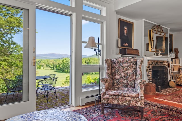 26 Balcony Seat Vw, Conway, NH 03860 - sitting room featuring a baseboard heating unit, wood finished floors, a brick fireplace, and a mountain view