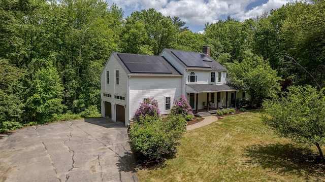 11 Rabbit Ln, Barrington, NH 03825 - view of front of house featuring covered porch, concrete driveway, a front lawn, a garage, and solar panels