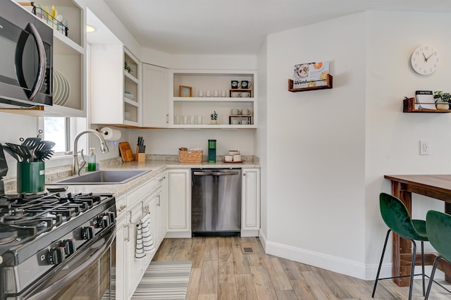 270 Beechnut Dr, Conway, NH 03860 - kitchen with appliances with stainless steel finishes, open shelves, a sink, light wood finished floors, and white cabinets