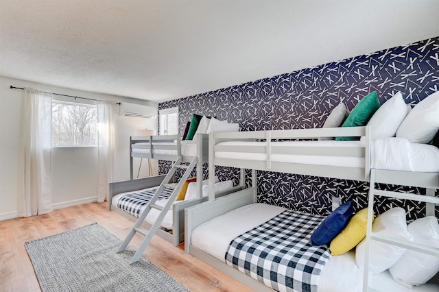 270 Beechnut Dr, Conway, NH 03860 - bedroom with wallpapered walls, wood finished floors, a wall mounted air conditioner, and baseboards