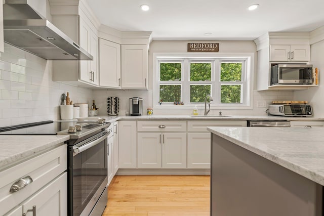 78 Hitching Post Ln, Bedford, NH 03110 - kitchen featuring stainless steel appliances, wall chimney exhaust hood, a sink, light wood-style floors, and recessed lighting