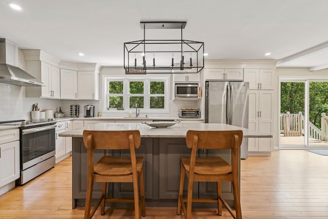 78 Hitching Post Ln, Bedford, NH 03110 - kitchen featuring stainless steel appliances, wall chimney range hood, a sink, a kitchen island, and tasteful backsplash