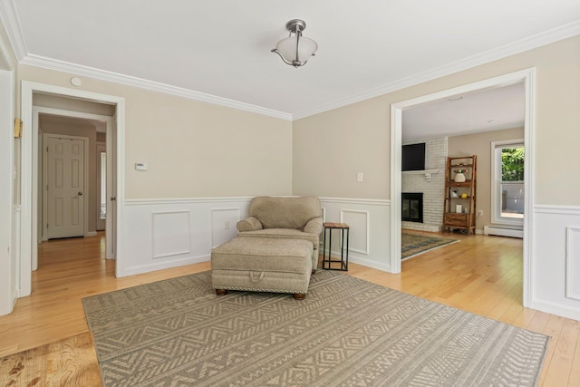 78 Hitching Post Ln, Bedford, NH 03110 - living area with light wood finished floors, a baseboard heating unit, ornamental molding, wainscoting, and a brick fireplace