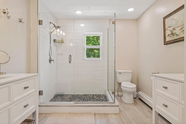 78 Hitching Post Ln, Bedford, NH 03110 - bathroom with a baseboard heating unit, vanity, toilet, a stall shower, and baseboards