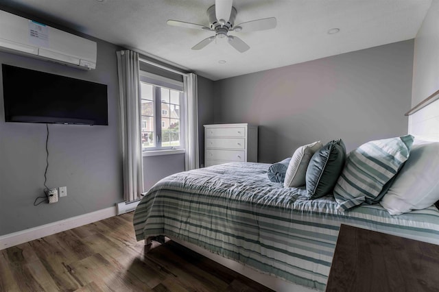 82 Garden Cir, Laconia, NH 03246 - bedroom featuring wood finished floors, an AC wall unit, baseboard heating, baseboards, and ceiling fan