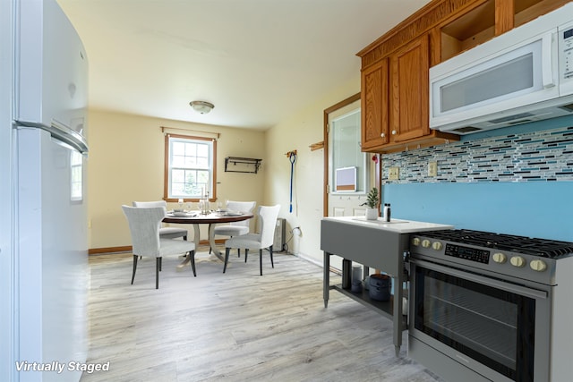 2 Ramsey Dr, Rochester, NH 03839 - kitchen featuring white appliances, brown cabinets, backsplash, light wood finished floors, and baseboards