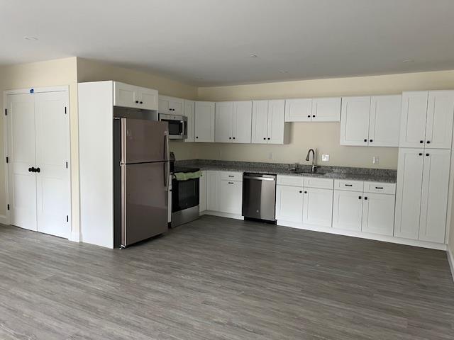 725 Central Ave Unit 103, Dover, NH 03820 - kitchen with appliances with stainless steel finishes, dark wood finished floors, white cabinets, and dark countertops