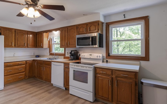 353 N St, Jaffrey, NH 03452 - kitchen featuring white appliances, a sink, brown cabinetry, light countertops, and light wood-type flooring