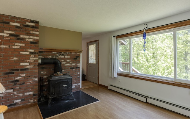 353 N St, Jaffrey, NH 03452 - living area with a baseboard radiator, wood finished floors, a wood stove, and baseboards