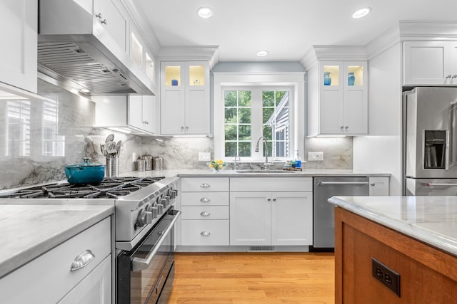6 Tannery Way, Kensington, NH 03833 - kitchen featuring appliances with stainless steel finishes, extractor fan, a sink, light wood-type flooring, and white cabinetry