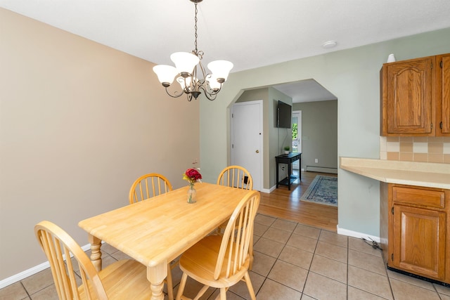 39 Orchard St, Laconia, NH 03246 - dining room with light tile patterned floors, arched walkways, a baseboard radiator, and a chandelier