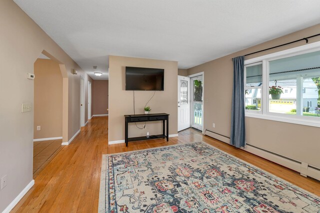 39 Orchard St, Laconia, NH 03246 - living room with wood finished floors, baseboard heating, baseboards, and arched walkways