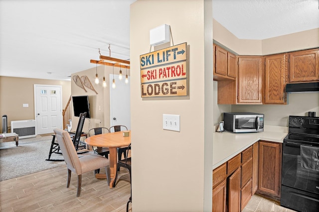 14 Monroe Dr Unit 92, Woodstock, NH 03293 - kitchen with black electric range oven, stainless steel microwave, under cabinet range hood, light wood-style floors, and light countertops