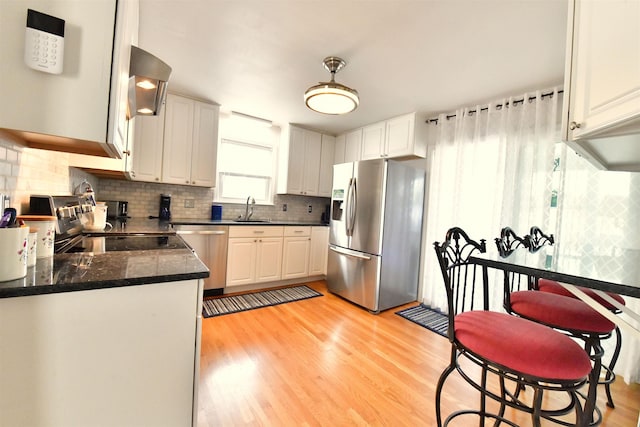 55 Harding St, Manchester, NH 03109 - kitchen featuring stainless steel appliances, a sink, backsplash, light wood-type flooring, and wall chimney exhaust hood